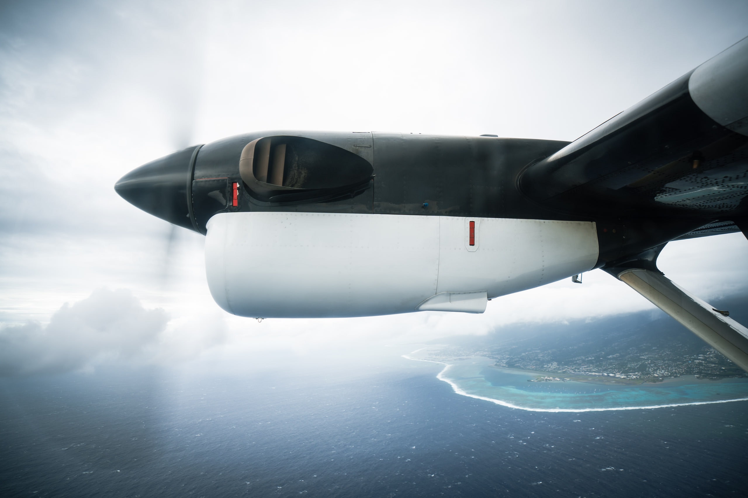 An aircraft wing and engine above a distant coastline