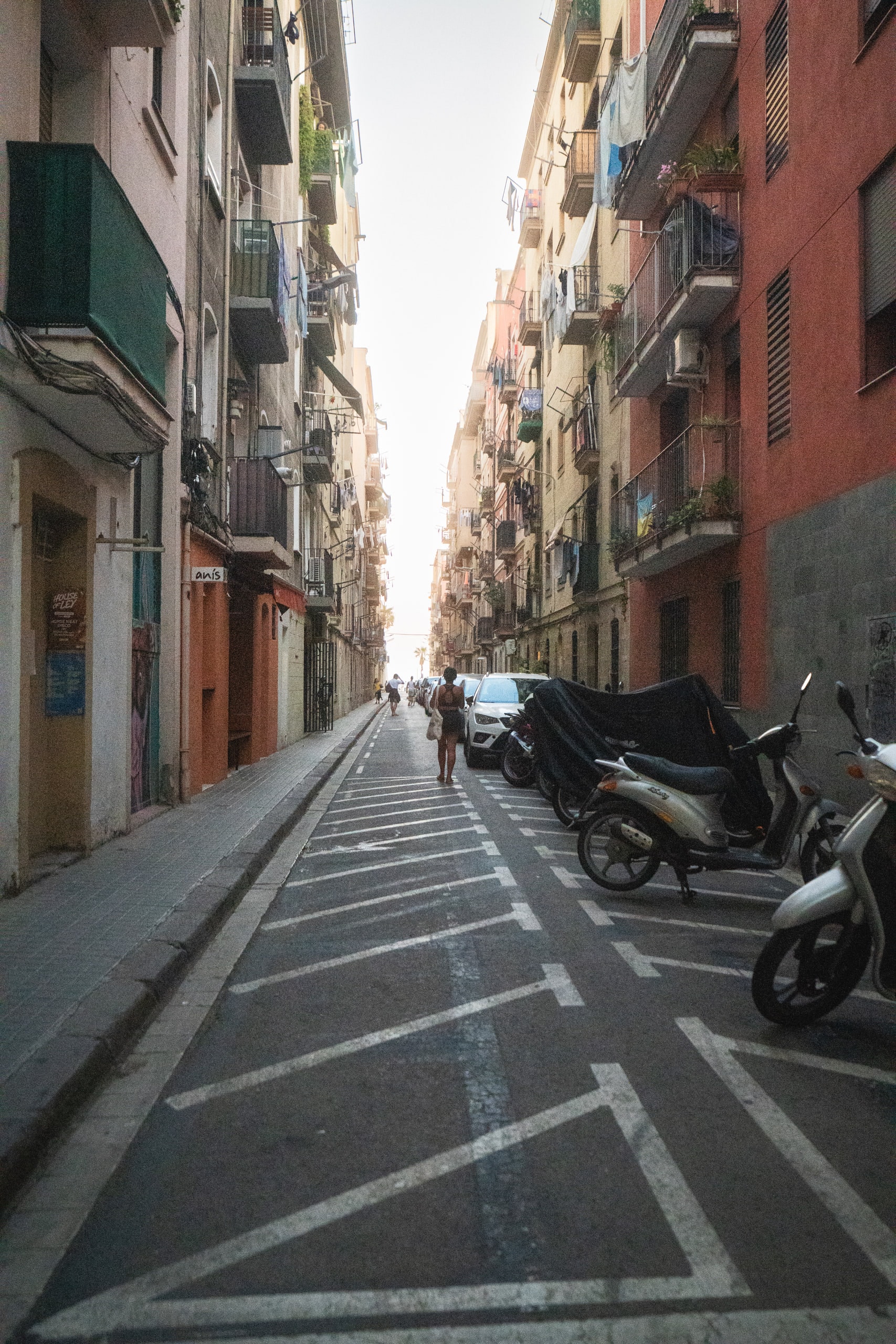 A narrow residential street with scooters parked along one side