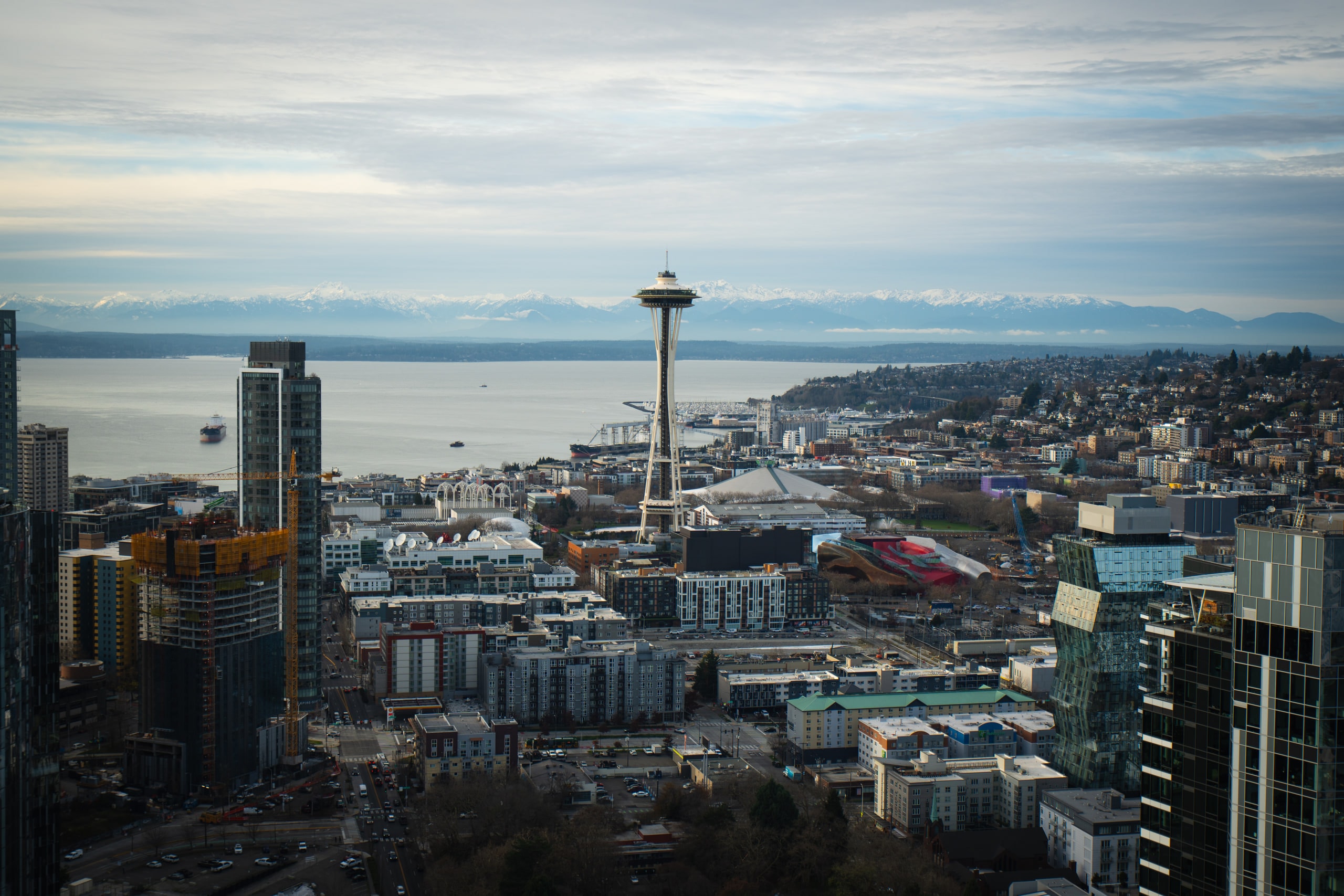 A city skyline with a tower, water and mountains beyond