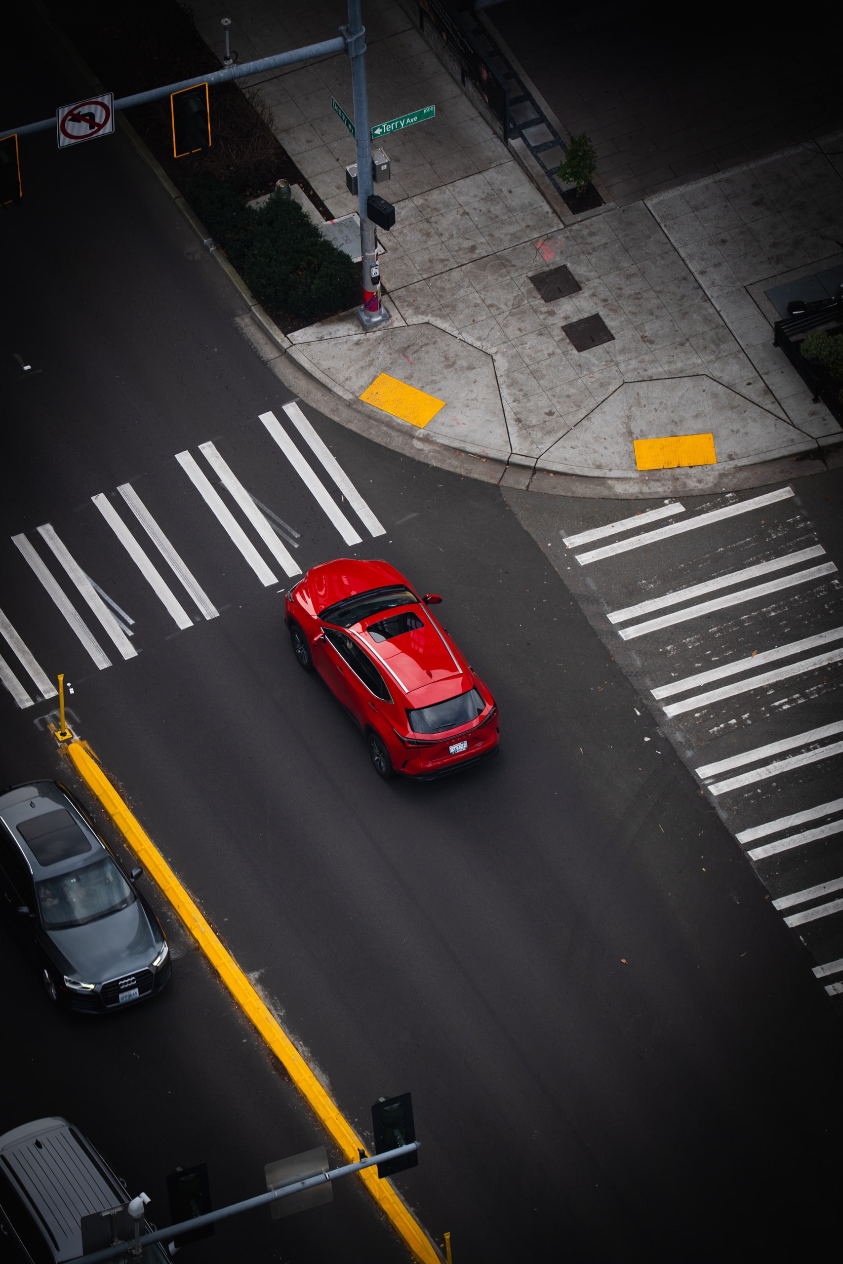 A red car crossing a marked intersection, seen from directly above