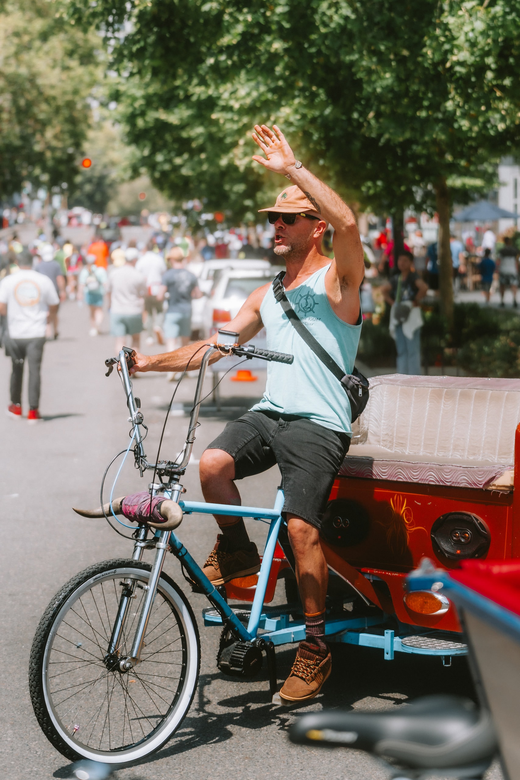 A man waving from a bicycle rickshaw during a street parade