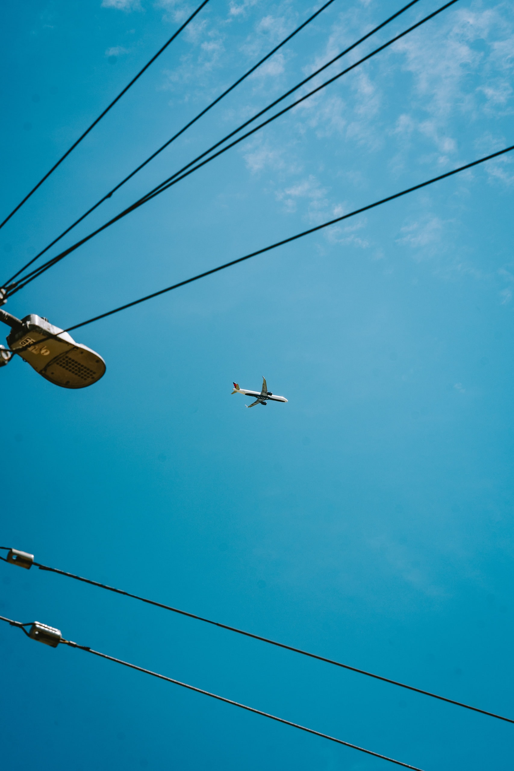 An aircraft framed between overhead cables