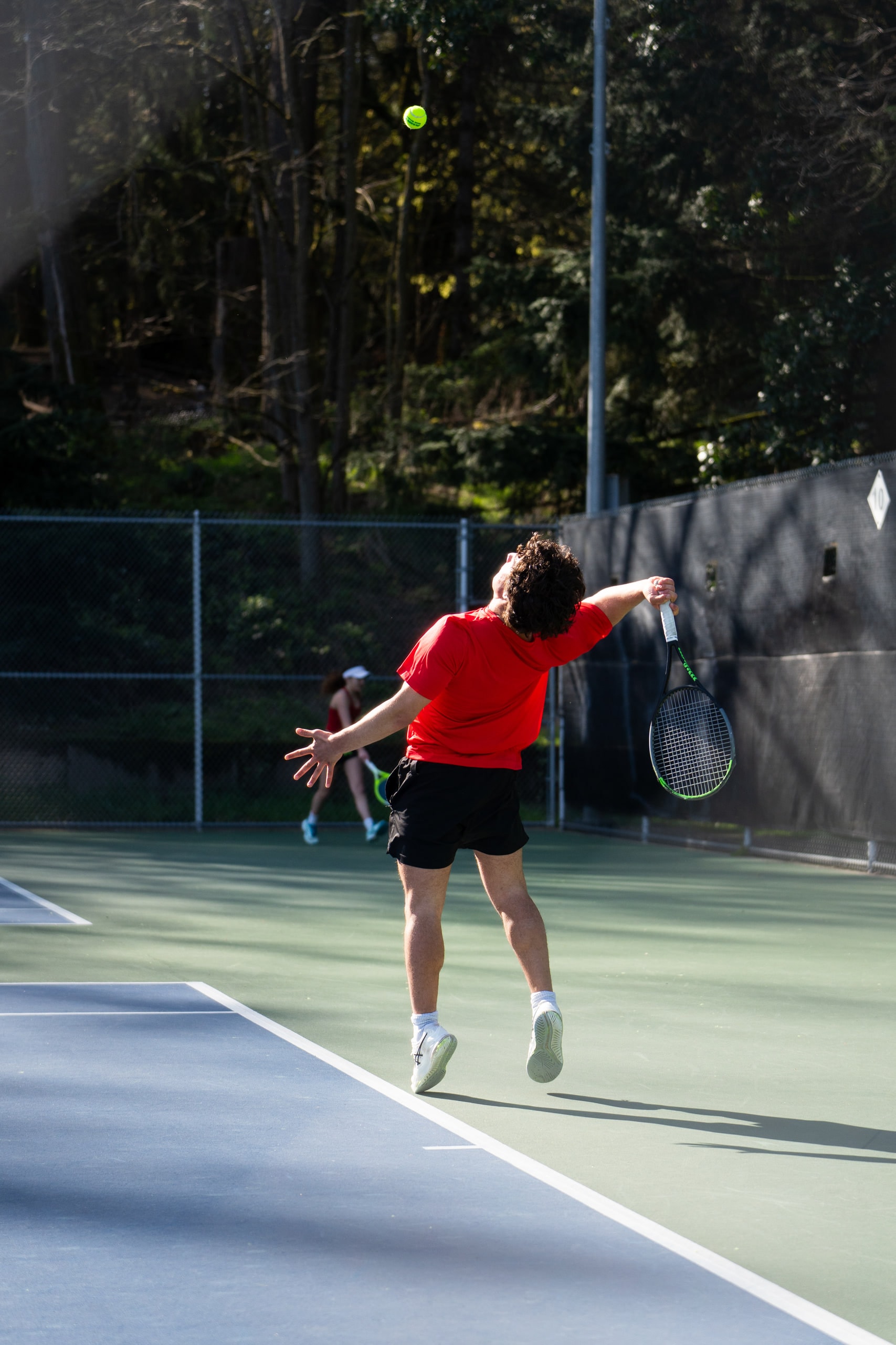 A player reaching for a serve on an outdoor court