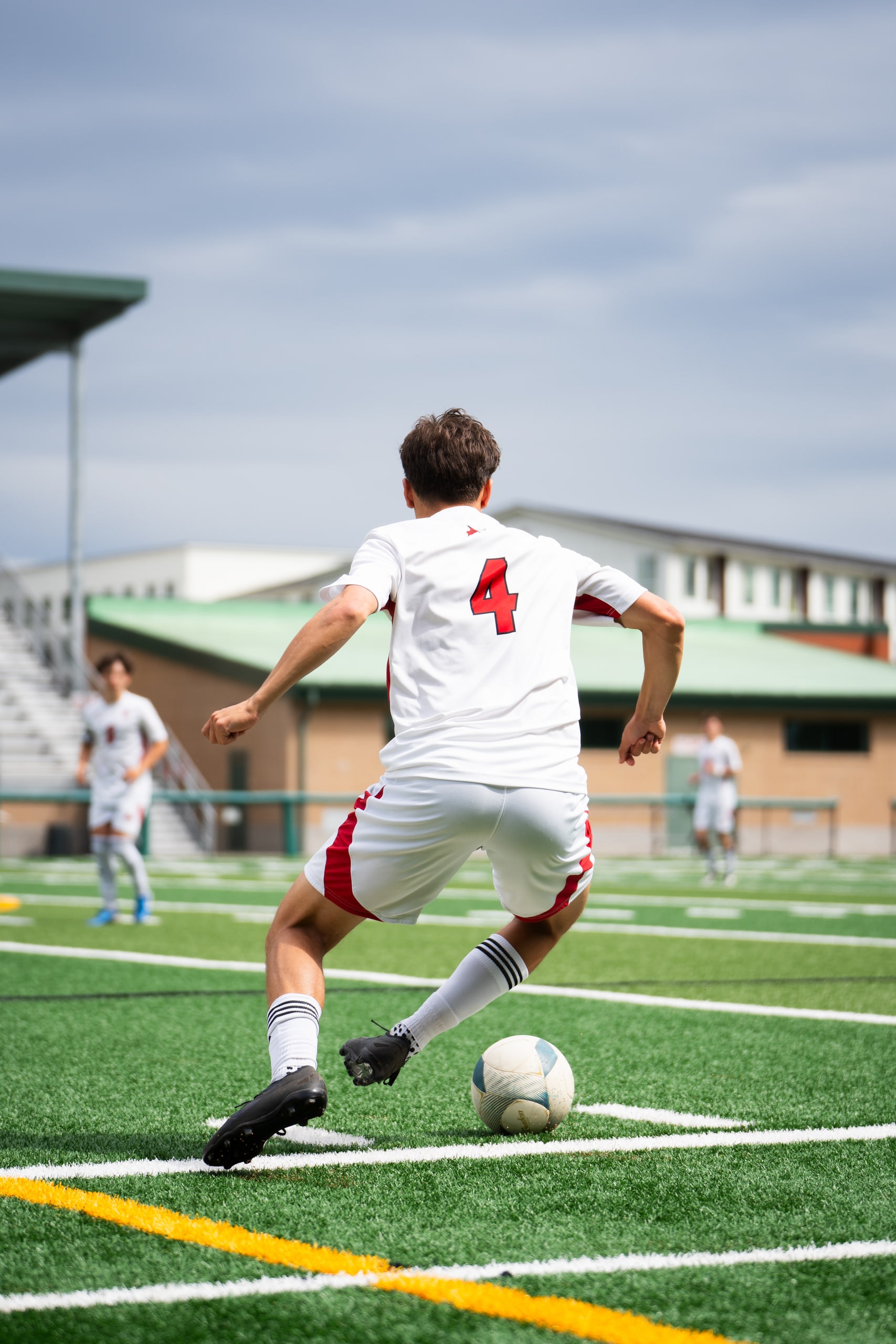 A midfielder in a number 4 shirt striking the ball