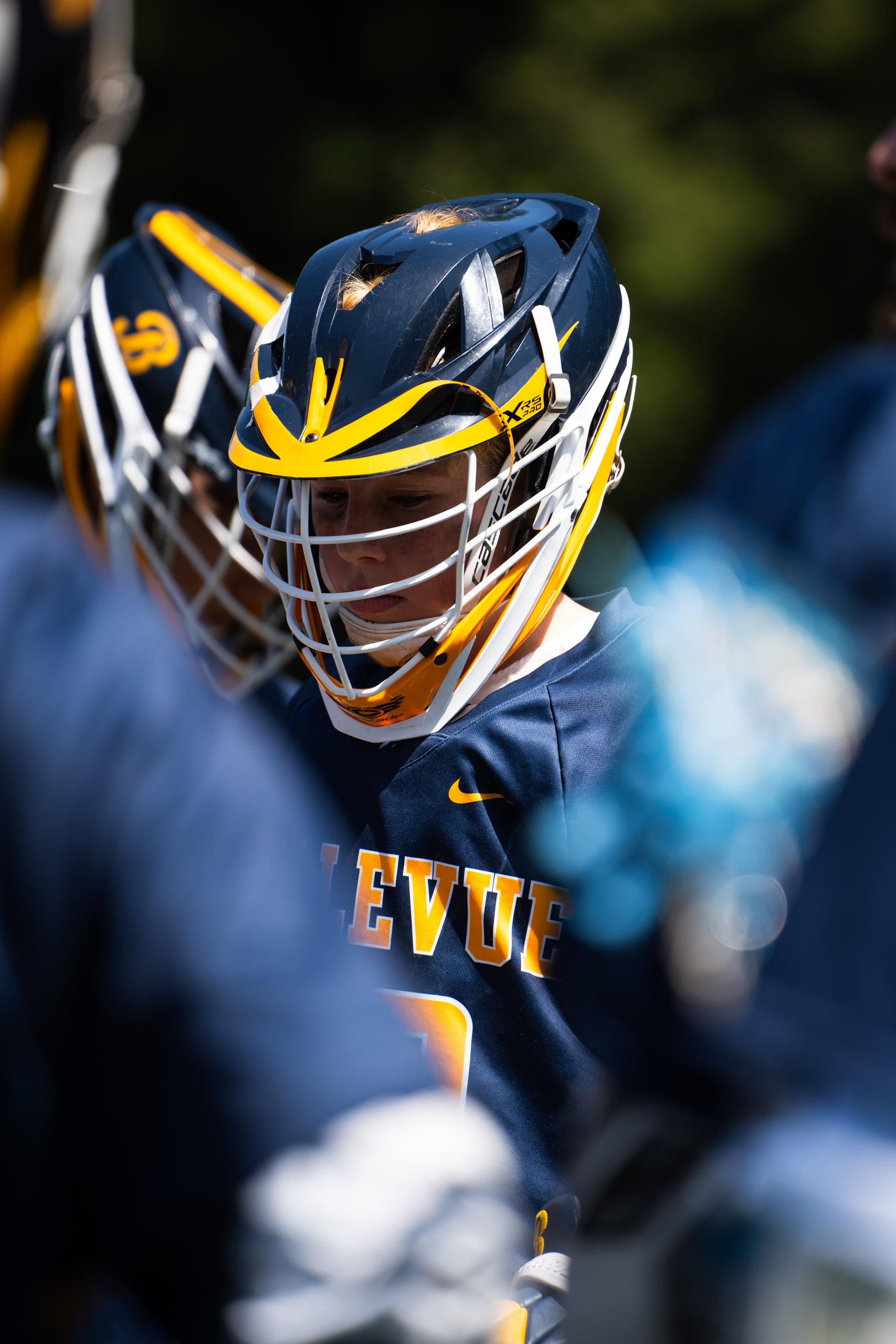 A lacrosse player in a blue and gold helmet