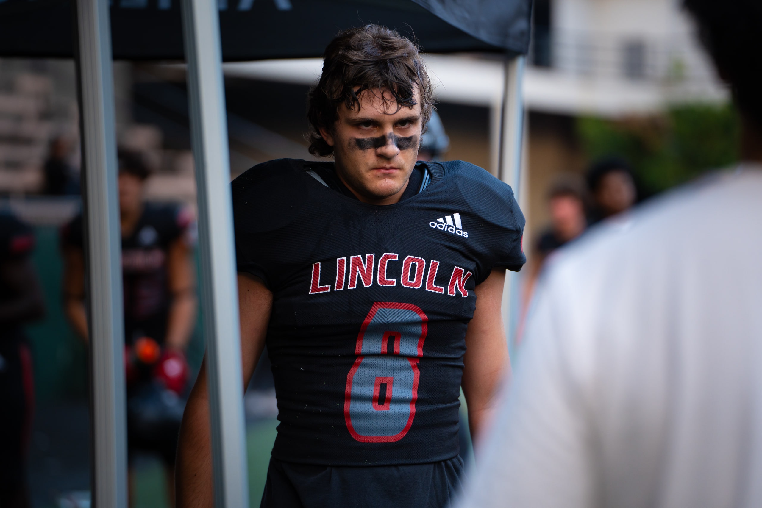 A player in a Lincoln number 6 jersey looking out from the sideline