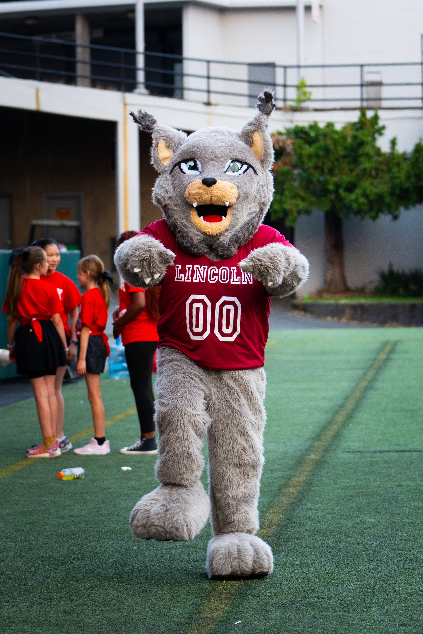 The Lincoln Lynx mascot with both arms raised beside the track