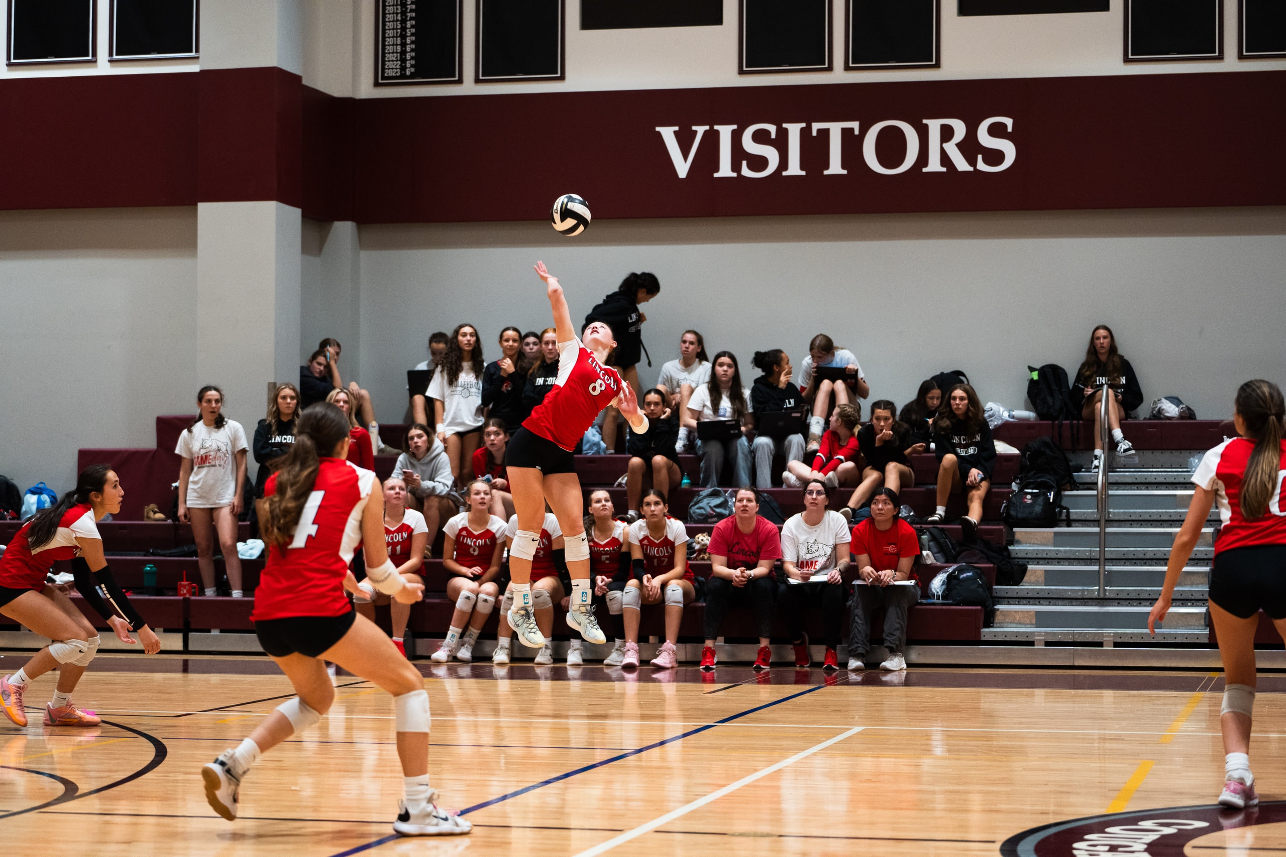 A player serving with the bench watching behind her