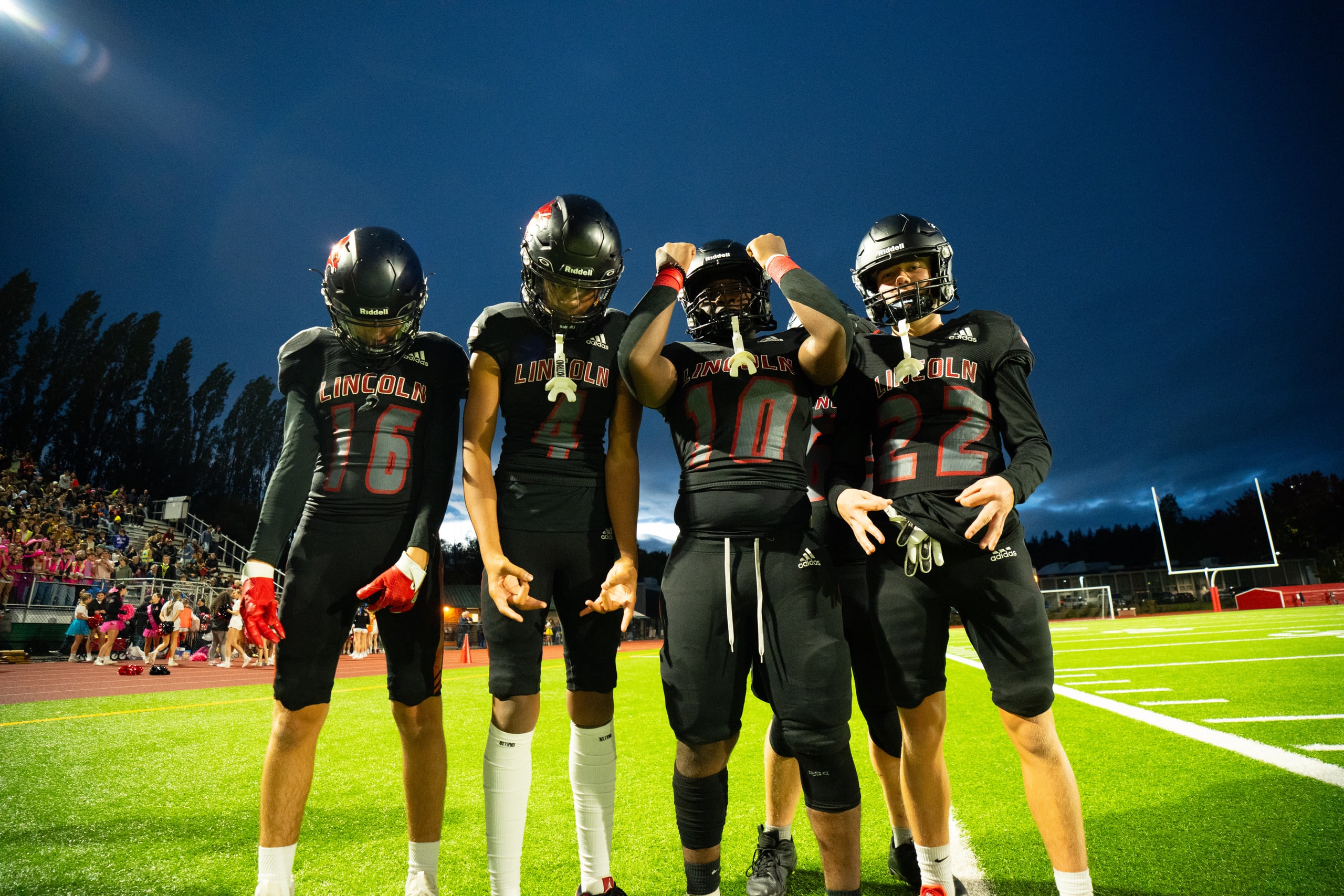 Four players standing together under floodlights at dusk