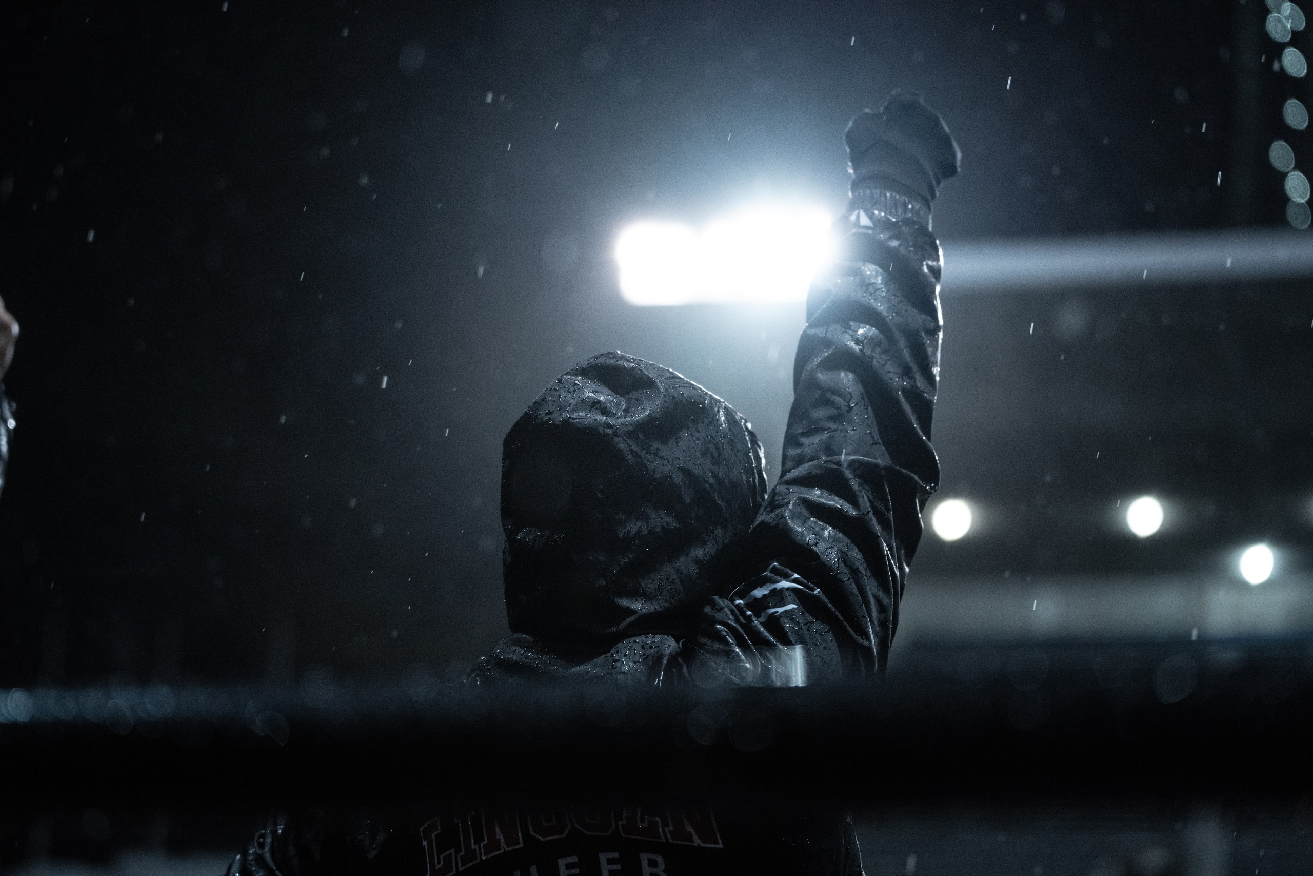 An official signalling with one arm raised in the rain under floodlights