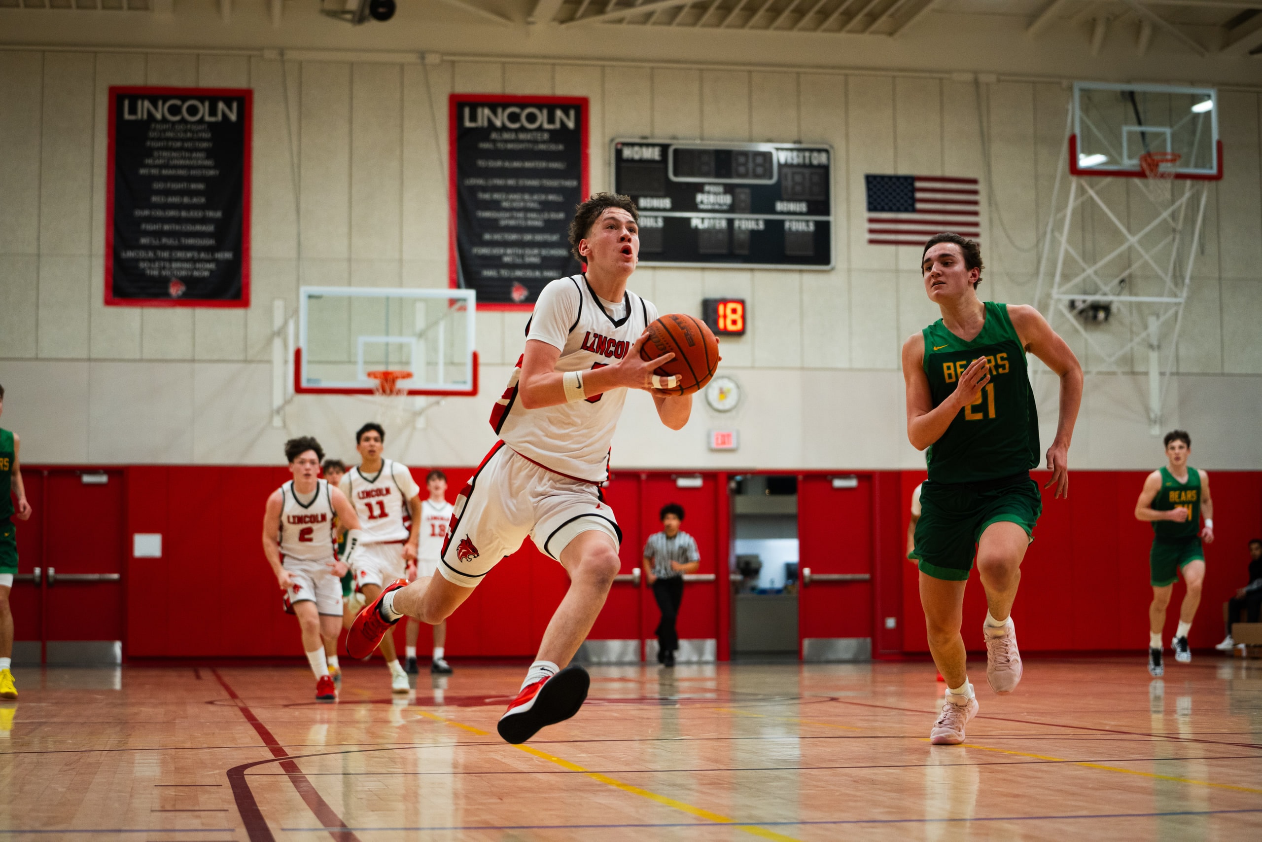 A basketball player driving to the rim past a defender