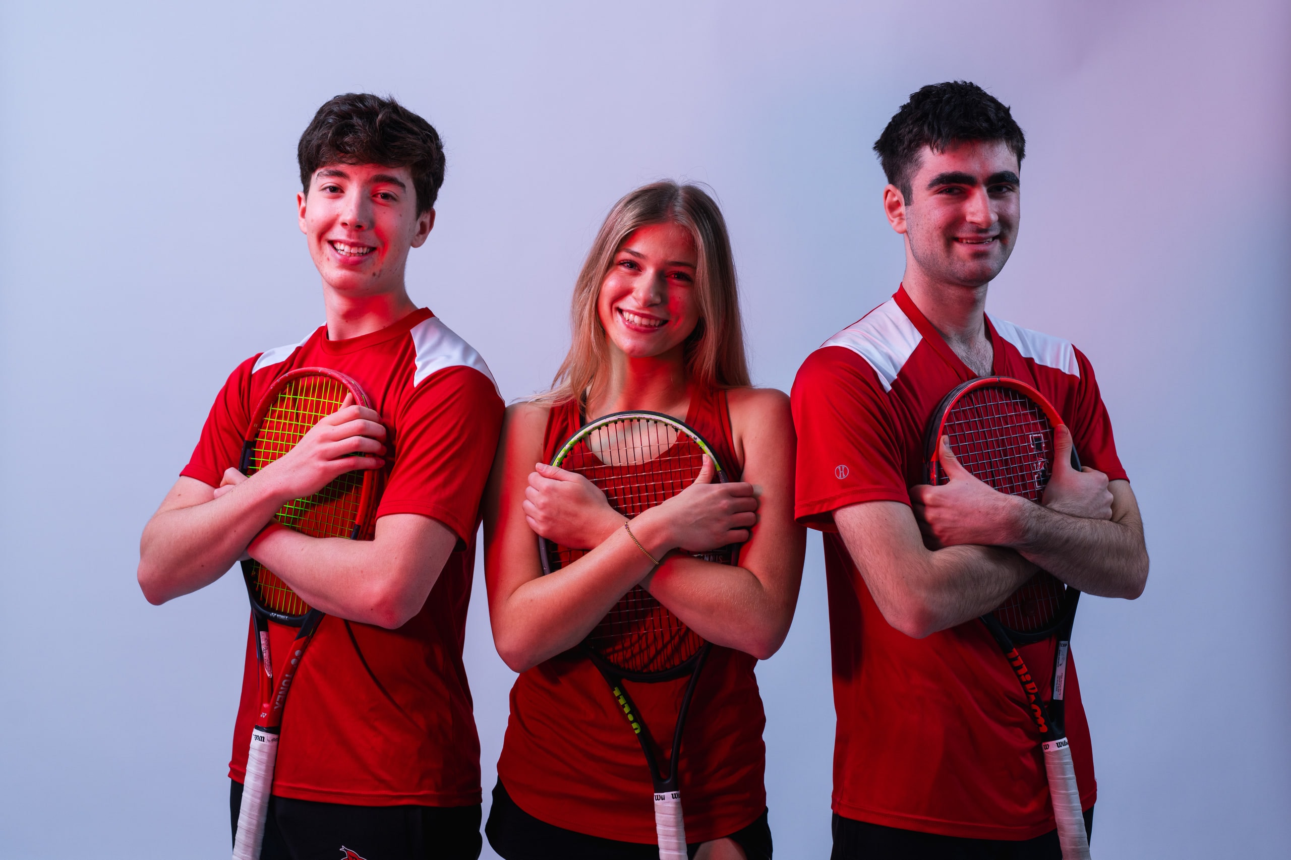 Three players standing with rackets held across their chests