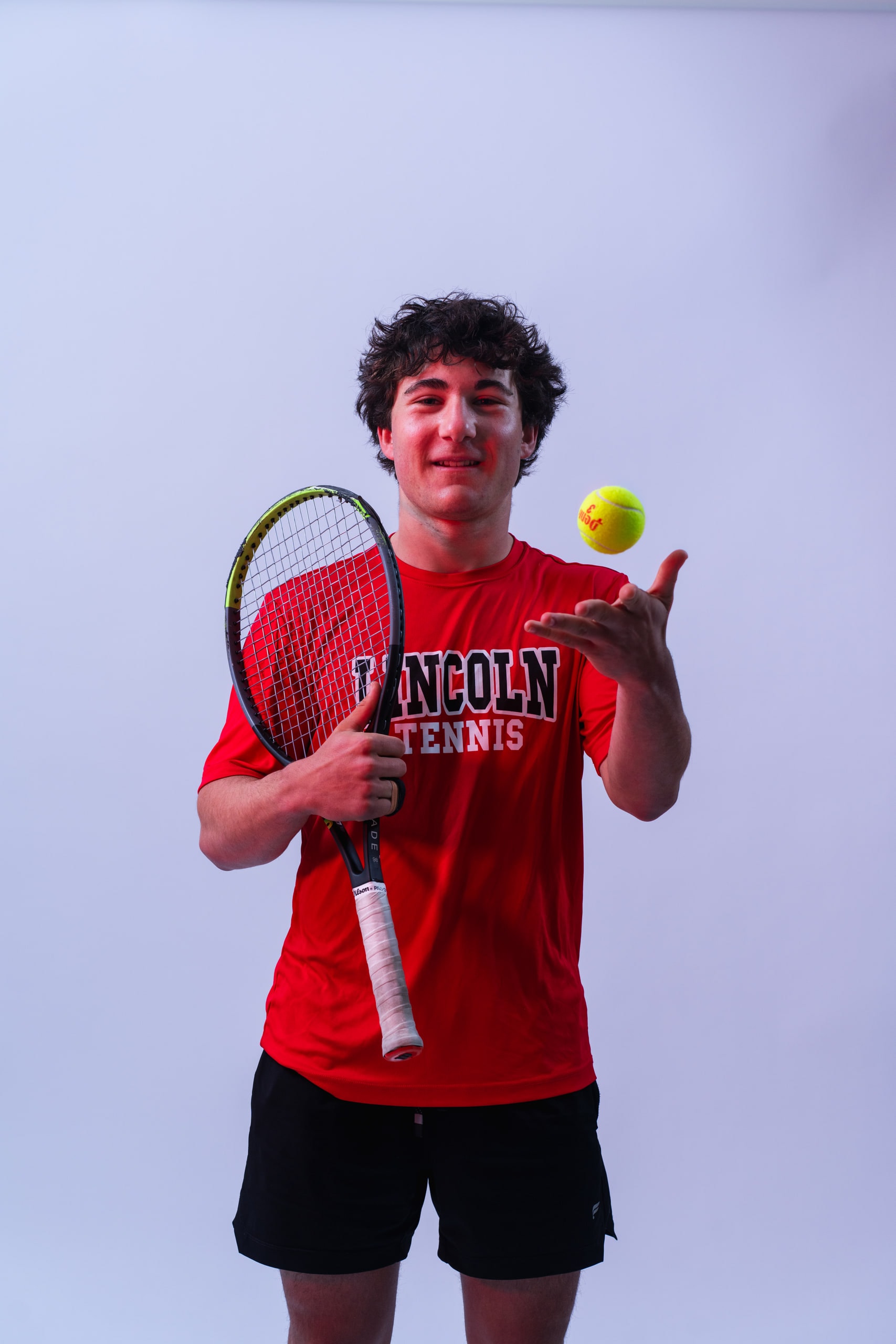 A tennis player tossing a ball beside his racket in the studio